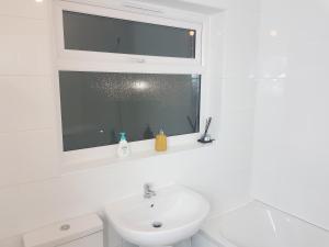 a white bathroom with a sink and a window at Kunda House Oliver in Birmingham