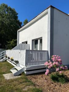 a white house with a porch and some flowers at Zacisze Nest - noclegi blisko plaży in Mielno