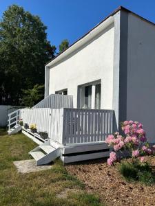 une maison blanche avec une clôture blanche et des fleurs dans l'établissement Zacisze Nest - noclegi blisko plaży, à Mielno