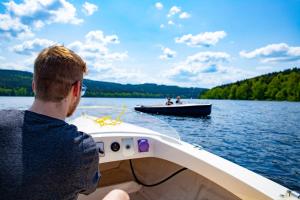 a man is on a boat on a lake at Amenity Hotel & Resort Lipno in Lipno nad Vltavou
