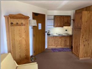 a kitchen with wooden cabinets and a door to a kitchen with a sink at Plose Parkhotel - Residence in Plancios