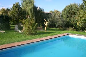 a blue swimming pool in a yard with a garden at La Fratta Art - House in Marsciano