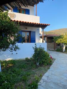 a white house with blue doors and a pathway at Esperides in Batsi