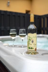 een fles wijn zittend op een tafel met twee wijnglazen bij Accomo Apartmanház in Siófok
