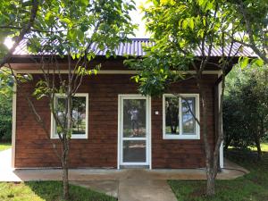 una casa pequeña con ventanas blancas y árboles en Vse Dlya Vas Guest House, en Gudauta