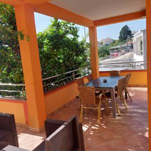 patio con mesa y sillas en el balcón en 5 rooms apartman en Barbat na Rabu