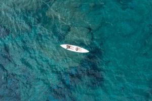 a white surfboard in the middle of the ocean at Eco Village Baia Delle Ginestre in Teulada