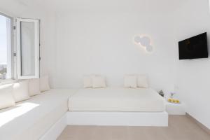 una camera da letto bianca con un letto bianco e una finestra di VOCA HOTEL & SUITES a Kamari