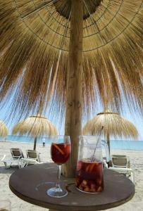 un tavolo con un bicchiere di vino e un ombrellone in spiaggia di Apartamento Guadiana Sol a Estepona
