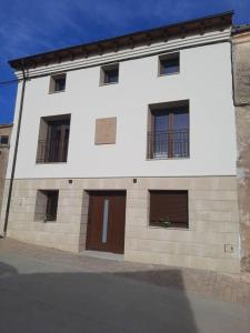 - un bâtiment blanc avec des portes et des fenêtres marron dans l'établissement Casa Rural Triticum, 