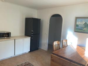 uma cozinha com um frigorífico preto e uma mesa em Björklunden em Gullringen