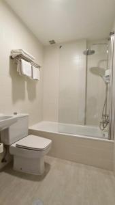 een witte badkamer met een toilet en een bad bij HOTEL RST. PADORNELO 