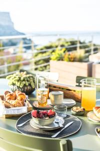 - une table avec des aliments pour le petit-déjeuner et des boissons sur un balcon dans l'établissement Suites 23, à Cassis