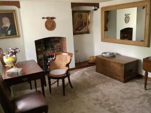 a living room with a table and a chair and a fireplace at Bwthyn Cudd in Westbury