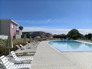 a row of lounge chairs and a swimming pool at Grazioso in Bibione