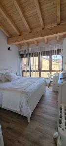 Schlafzimmer mit einem großen weißen Bett und Holzdecken in der Unterkunft Apartamentos Les Texuques in Nueva de Llanes