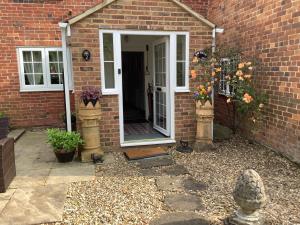 a front door of a brick house with flowers at Bwthyn Cudd in Westbury +9 photos