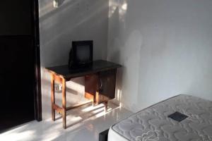 Zimmer mit einem Bett und einem Schreibtisch mit einem TV. in der Unterkunft OYO Life 92647 Edelweis Homestay in Tuban