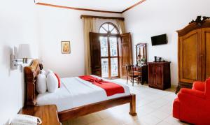 um quarto com uma cama e uma cadeira vermelha em Hotel Real La Merced em Granada