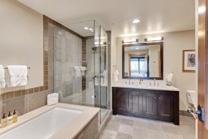 a bathroom with a tub and a shower and a sink at Edgemont 2306 - Luxury Condo - True Ski-in Ski-out Access & Winter Shuttle! in Steamboat Springs +12 photos