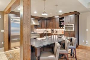 a kitchen with a large island with chairs around it at Edgemont 2306 - Luxury Condo - True Ski-in Ski-out Access & Winter Shuttle! in Steamboat Springs