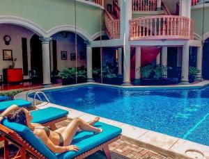 a woman laying on chairs in a swimming pool at Hotel Real La Merced in Granada