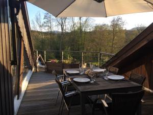 a wooden table with chairs and an umbrella on a deck at Le repaire de Camille - LOFT in Birkenwald