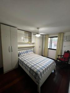 ein Schlafzimmer mit einem Bett und einem roten Stuhl in der Unterkunft Recreio, a praia mais charmosa do RJ! in Rio de Janeiro