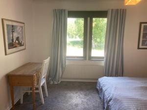 a bedroom with a bed and a desk and a window at Björklunden in Gullringen