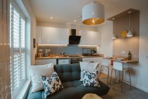 a living room with a couch and a kitchen at Blooms Apartment in Marple