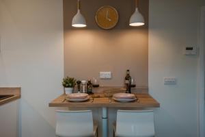 uma mesa com cadeiras e um relógio na parede em Blooms Apartment em Marple