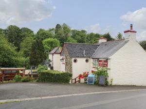 Un edificio blanco con un cartel delante. en Little Hamlin, en Callington