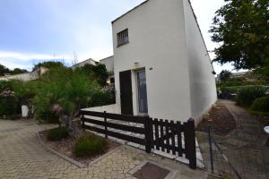 een klein wit huis met een hek ernaast bij Villa Naturiste "EDEN" Héliovillage 105 in Cap d'Agde