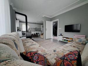 een woonkamer met een bank en een flatscreen-tv bij ORTAKÖY VİLLA in Macka