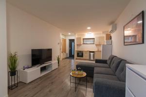 a living room with a couch and a tv at Római Panoráma apartman in Siófok