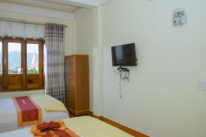 a bedroom with two beds and a tv on the wall at HOA PHUONG PHONG NHA Hotel in Phong Nha
