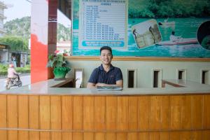 um homem sentado num balcão num bar em HOA PHUONG PHONG NHA Hotel em Phong Nha