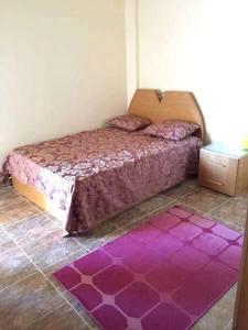 ein Schlafzimmer mit einem lila Bett und einem lila Teppich in der Unterkunft Chalet in Mena 4-North Coast in Dawwār ‘Abd al ‘Aţī Abū ‘Ajūz