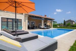uma piscina com um guarda-chuva laranja ao lado de uma casa em Villa Istra Maružini by Solis Porec em Maružini