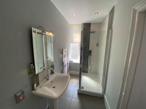 a white bathroom with a sink and a shower at The Broadway Hotel in Llandudno