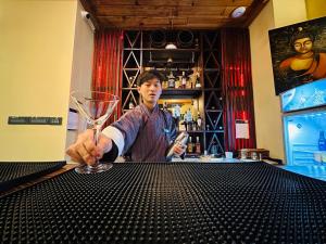 Um homem sentado num bar a segurar um copo de vinho. em Silver Cloud Hotel em Paro