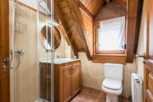 a bathroom with a toilet and a glass shower at Casa Artiga de Lin by SeaMount Rentals in Las Bordas