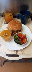 une assiette de nourriture avec un hamburger et un bol de légumes dans l'établissement ArtMotel & Bistro, à Haţeg