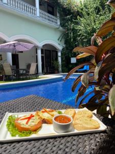 ein Teller mit Essen auf einem Tisch neben einem Pool in der Unterkunft Hotel Real La Merced in Granada