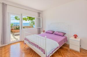 a bedroom with a white bed and a large window at Blu Breeze Apartments in Lokva Rogoznica