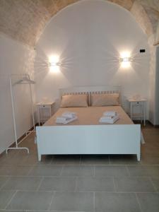 een slaapkamer met een wit bed en 2 tafels bij Studio Flat in White City in Ostuni
