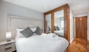 a bedroom with a large white bed and a mirror at Flat 2 in London
