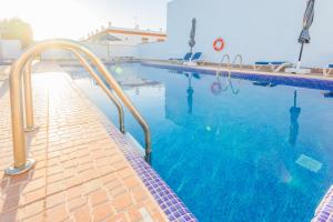 a swimming pool with blue water and metal rails at Villa la Dehesa in Conil de la Frontera