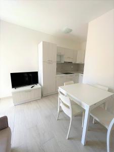 sala de estar con mesa blanca y cocina en Affittimoderni La Maddalena - MADA25 en La Maddalena