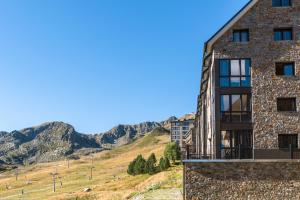 a building on a hill with mountains in the background at Pierre & Vacances Pas de la Casa Princesa in Pas de la Casa